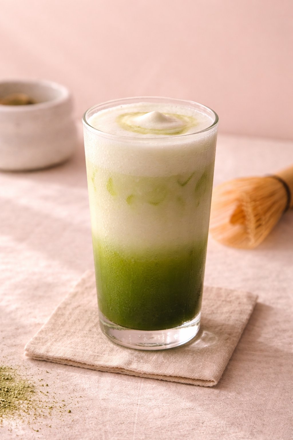 Matcha latte met groene lagen en melkschuim naast bamboe chasen
